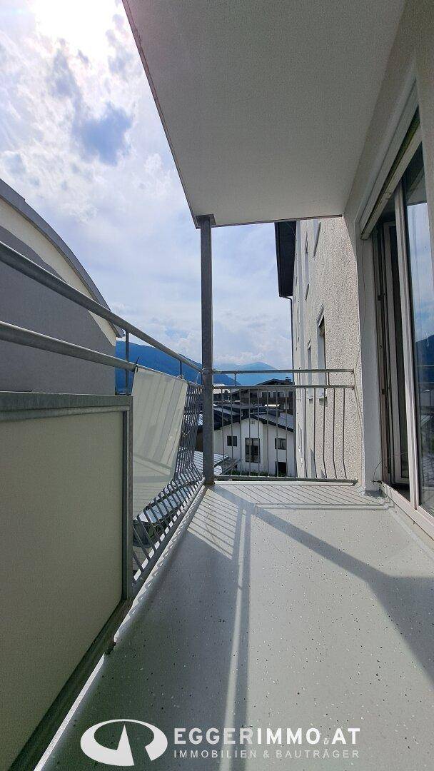 Geräumiger Balkon mit Blick auf die umliegende Bebauung und die beeindruckende Berglandschaft in der Ferne.
