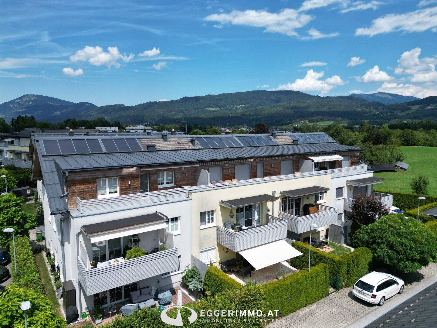 Moderner Wohnkomplex mit mehreren Einheiten, ausgestattet mit Balkonen und Photovoltaikanlagen auf dem Dach.