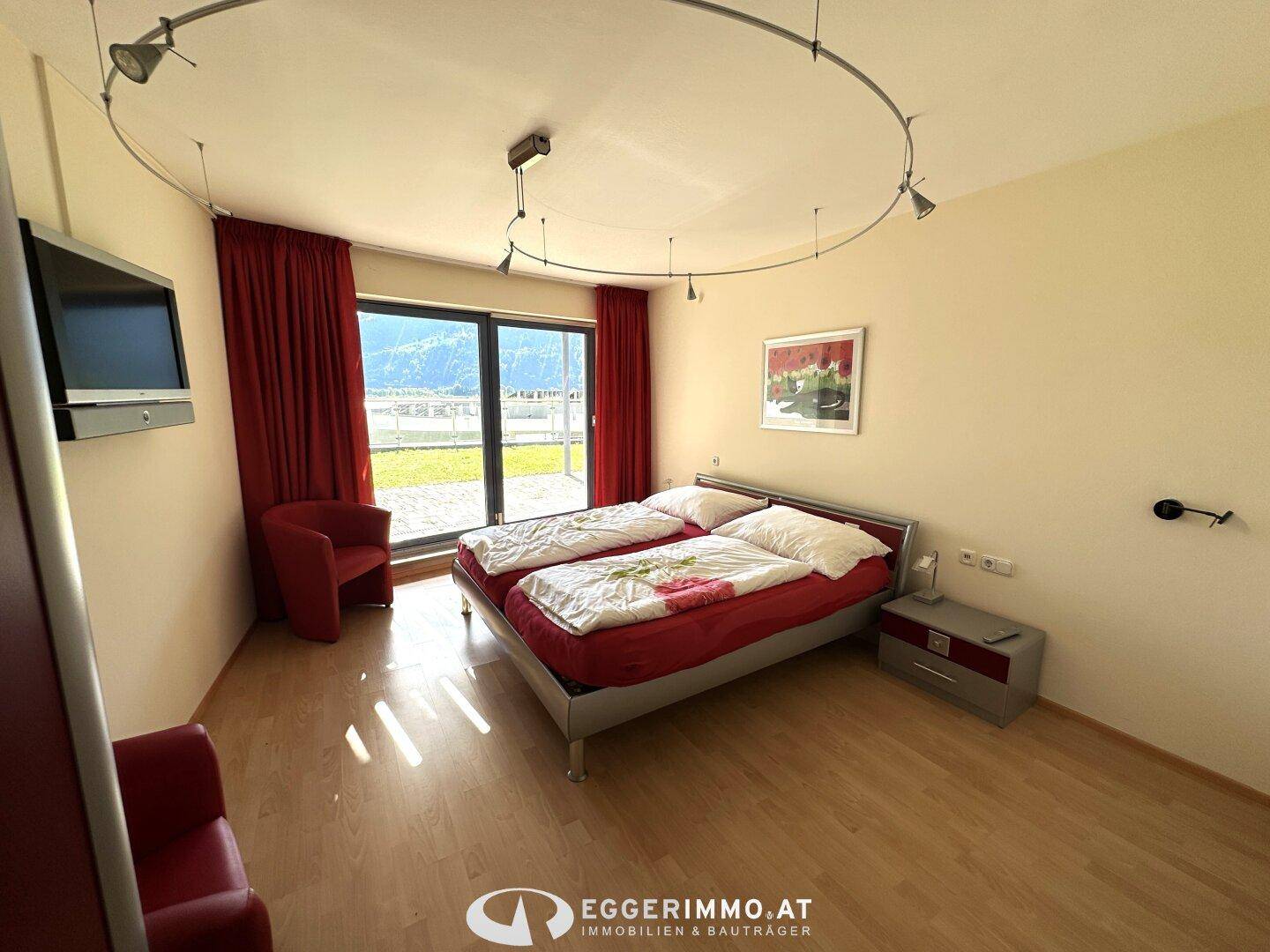 Helles Schlafzimmer mit zwei Einzelbetten, Holzfußboden und Zugang zu einem Balkon.
