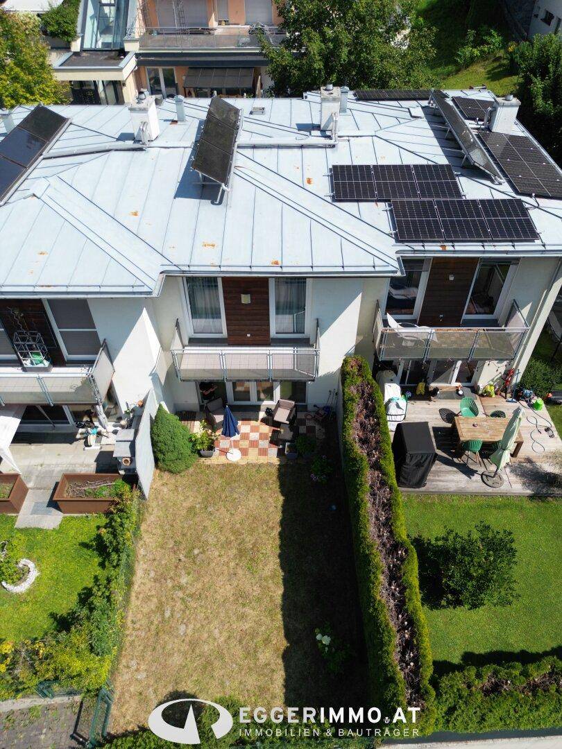 Dachansicht des Hauses mit Solaranlagen und Blick auf den privaten Gartenbereich mit Terrasse.