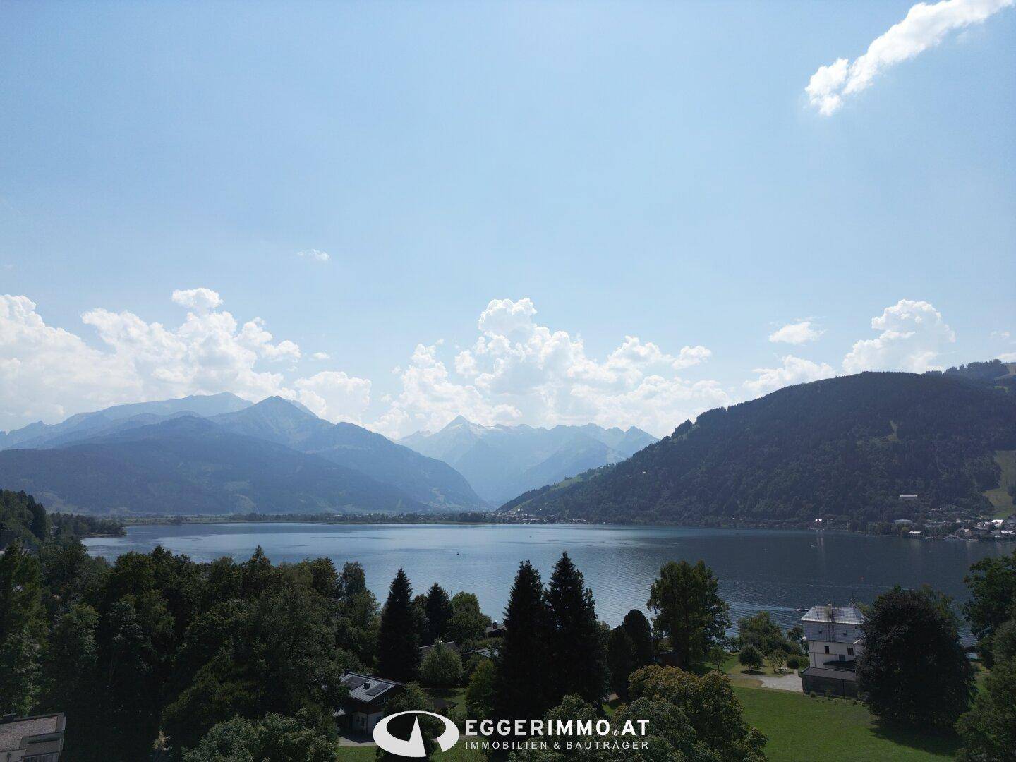 Atemberaubender Panoramablick auf den See und die umliegende Berglandschaft unter blauem Himmel.