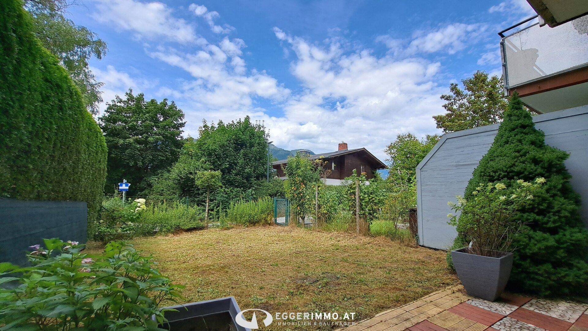 Kleiner privater Gartenbereich mit Rasenfläche und Hecke, umgeben von Bäumen und Natur.