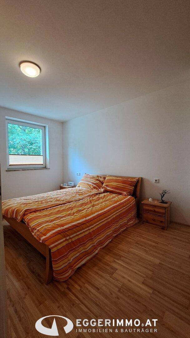 Schlafzimmer mit Doppelbett, Holzfußboden und Fenster, hell und freundlich gestaltet.