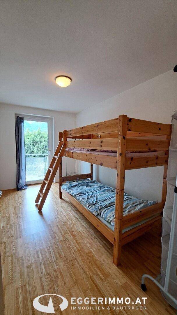 Kinderzimmer mit Etagenbett, Holzfußboden und Zugang zu einem Balkon.