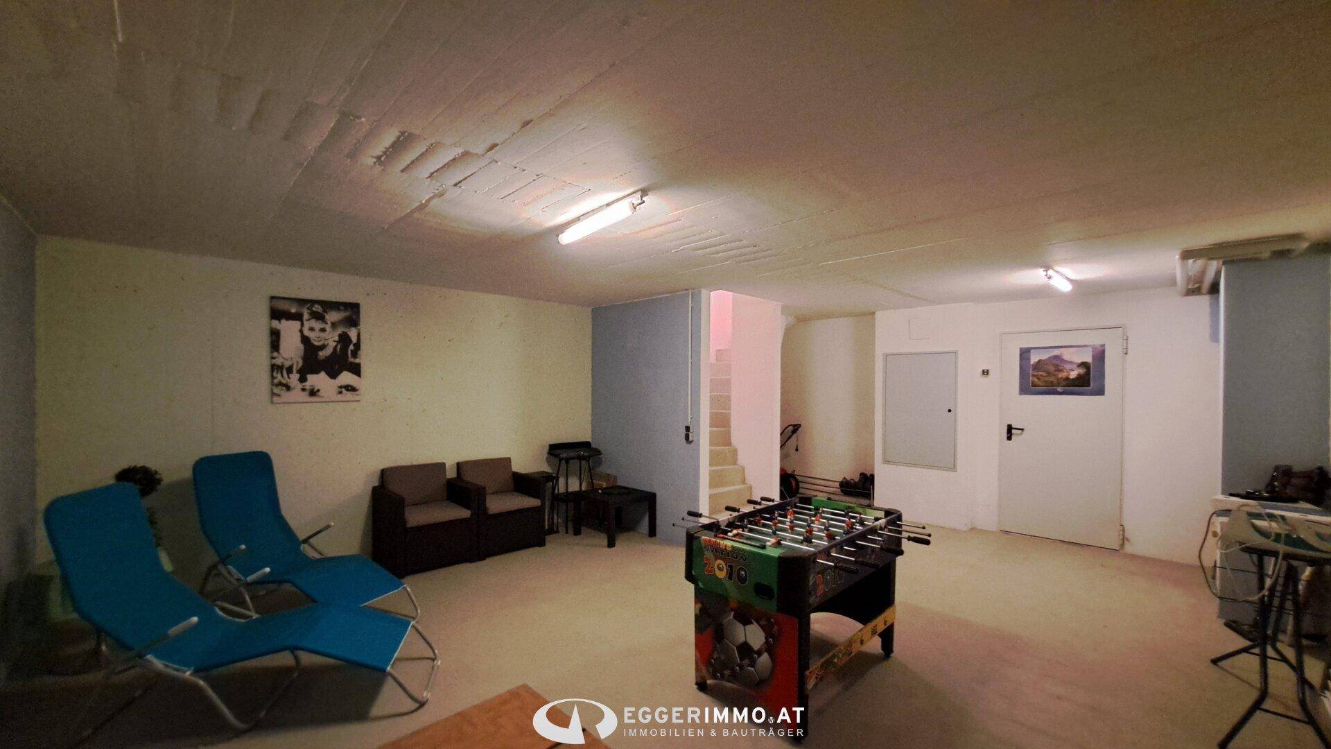 Großer Kellerraum mit Tischfußballtisch, Sitzgelegenheiten und Zugang zur Treppe.