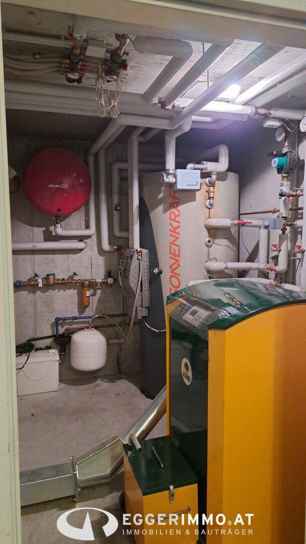 Heizungsraum mit Heizkessel, Warmwasserspeicher und sichtbaren Rohrleitungen.
