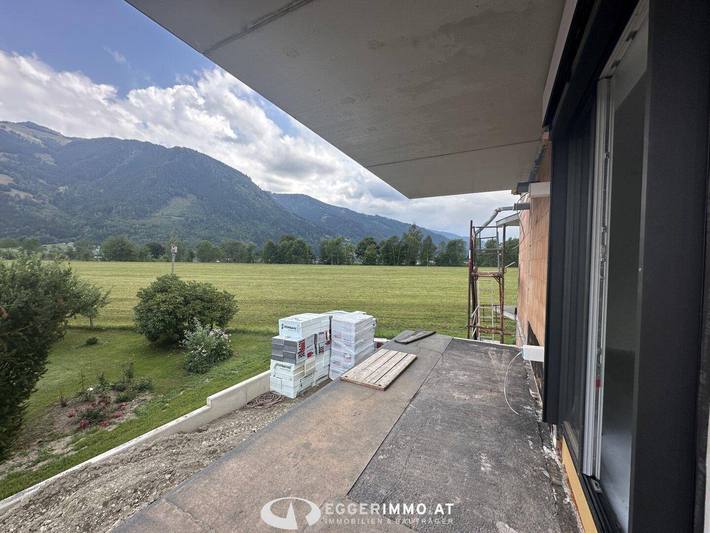 Unfertiger Balkon im Bau mit weitem Blick auf die grüne Landschaft und Berge.