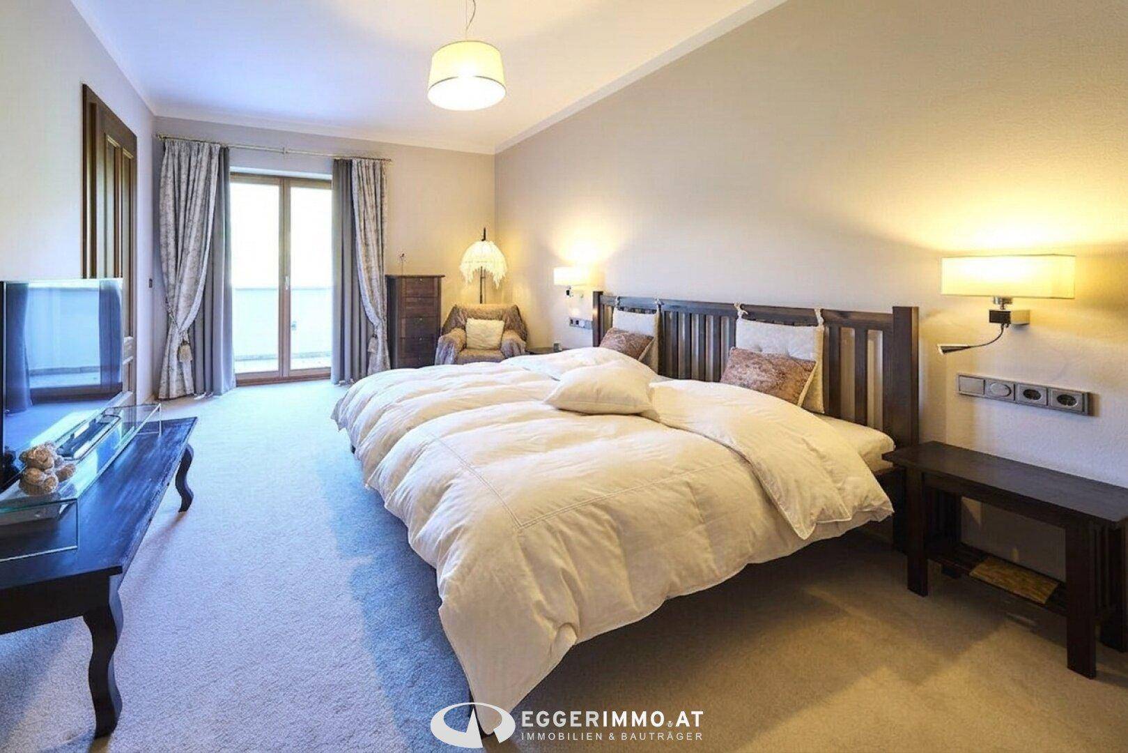 Geräumiges Schlafzimmer mit Teppichboden, Doppelbett und Zugang zu einem Balkon.