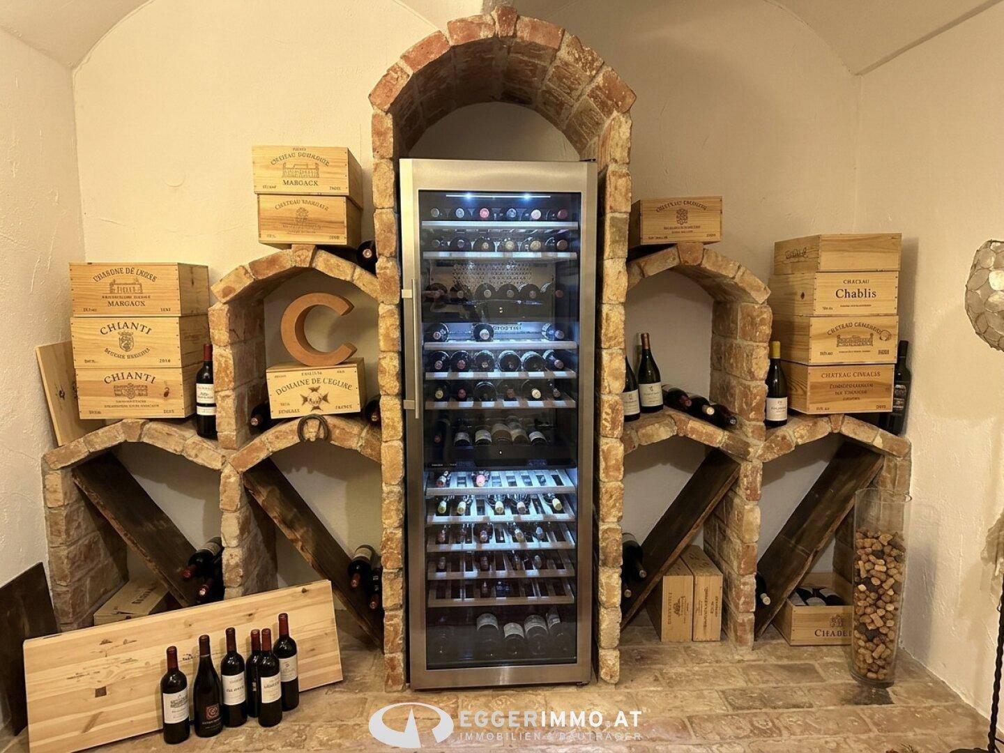 Rustikaler Weinkeller mit Ziegelgewölben, Weinkisten und einem modernen Weinkühlschrank.