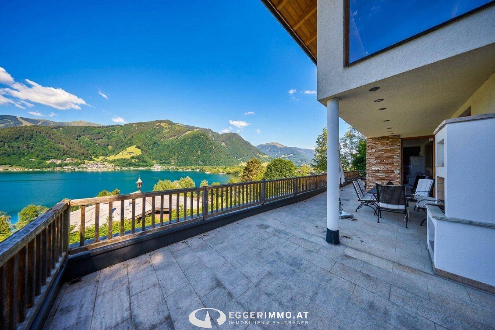 Große Steinterrasse mit Sitzgelegenheiten und weitem Blick auf den See und die umliegende Landschaft.