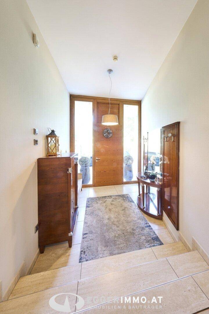 Heller Eingangsbereich mit Holztür, Fliesenboden und einer eleganten Kommode.