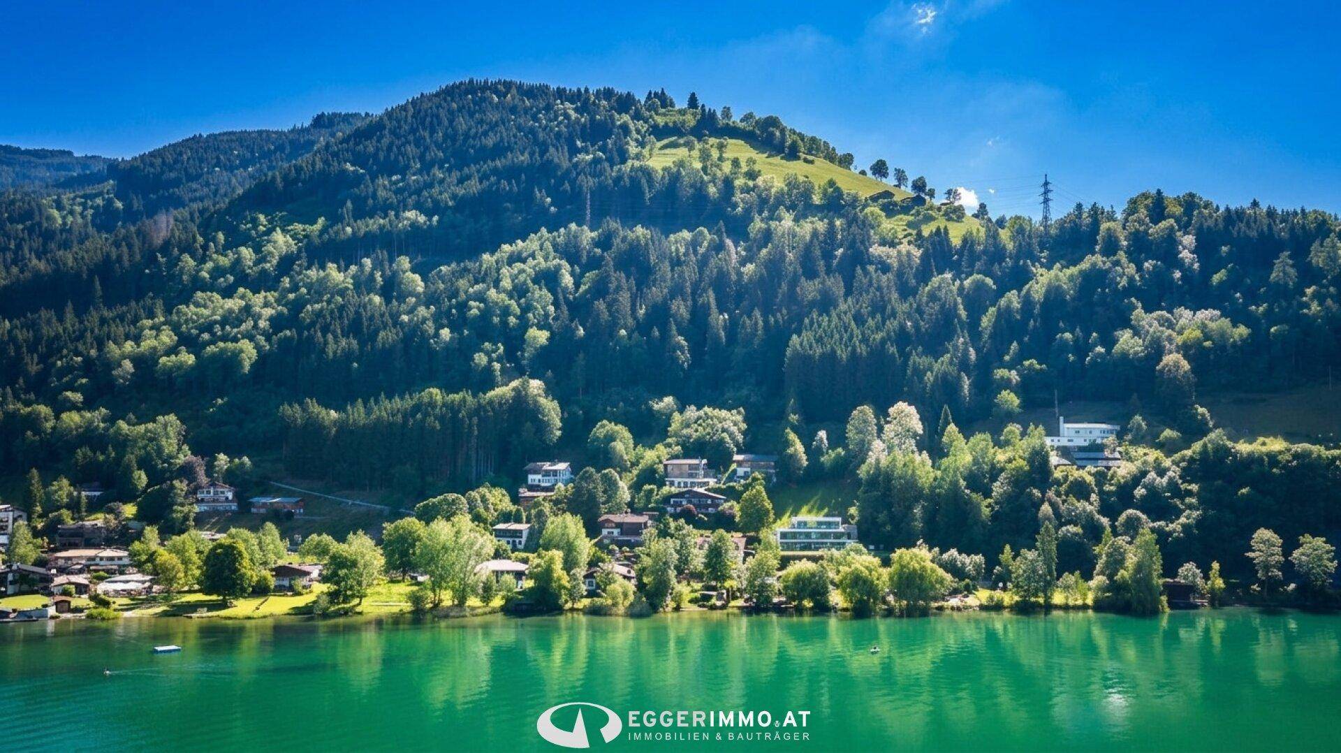 Weitläufiger Blick über den See mit bewaldeten Hügeln und vereinzelten Häusern am Ufer.