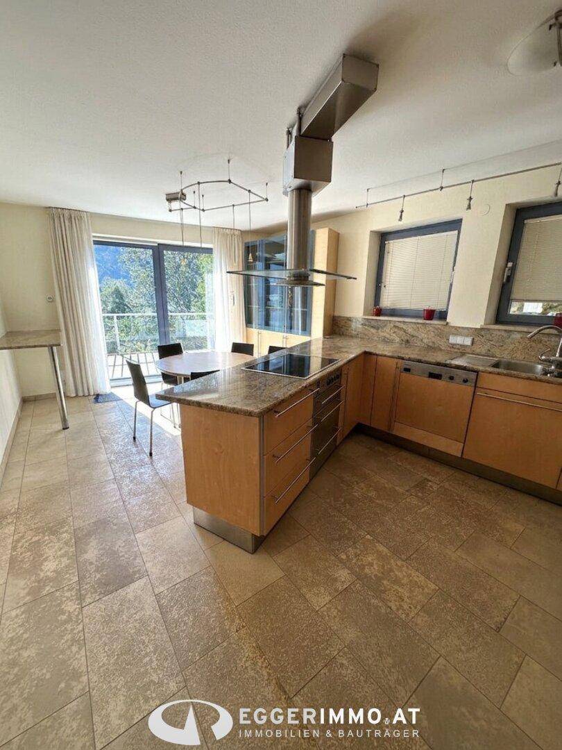Geräumige Wohnküche mit Essbereich, Granitarbeitsplatten, Fliesenboden und Zugang zu einem Balkon mit Bergblick.