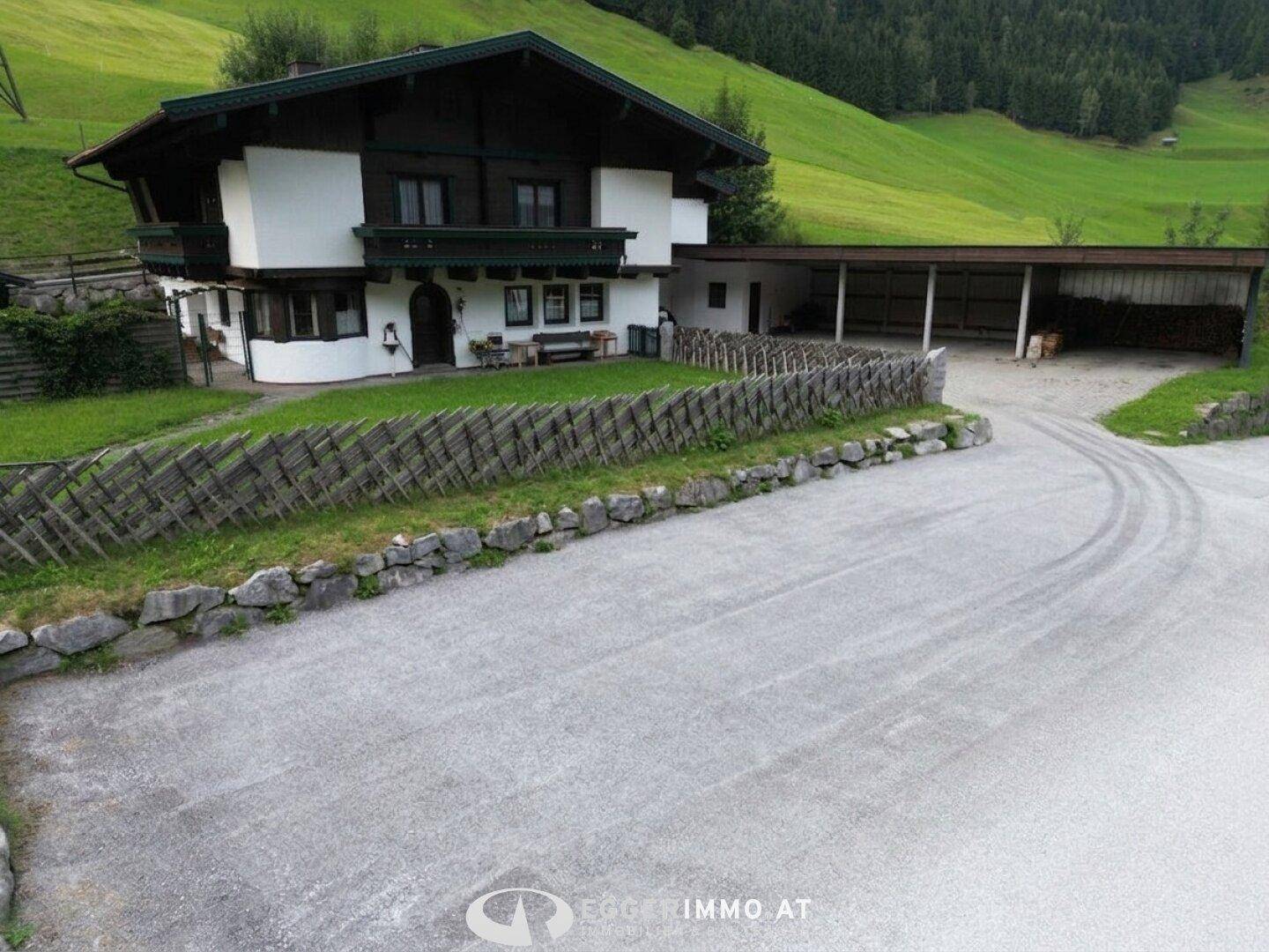 Traditionelles Wohnhaus mit gepflegtem Vorgarten und einer breiten Schotterzufahrt.