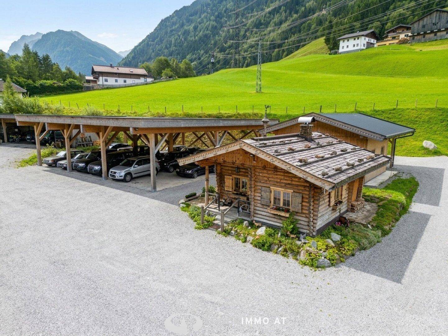 Geräumiger Carport mit begrüntem Dach und einer rustikalen Holzhütte, umgeben von Schotter.