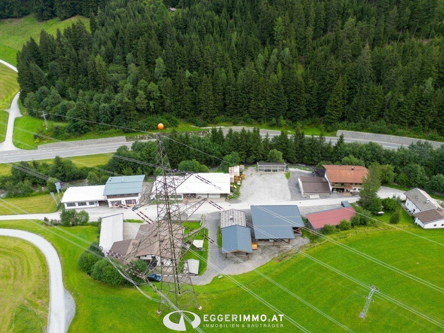 Panoramablick auf das Anwesen in einem Tal, umgeben von bewaldeten Bergen und grünen Wiesen.