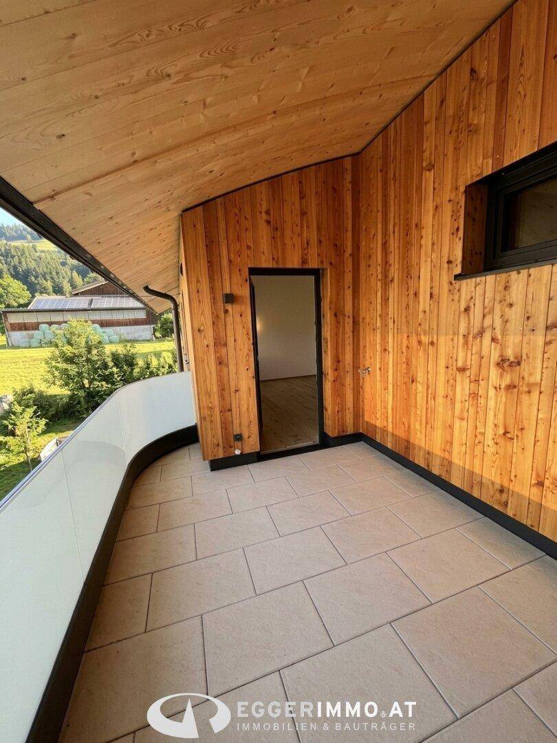 Breiter Balkon mit Fliesenboden, Holzverkleidung und weitem Blick ins Grüne.