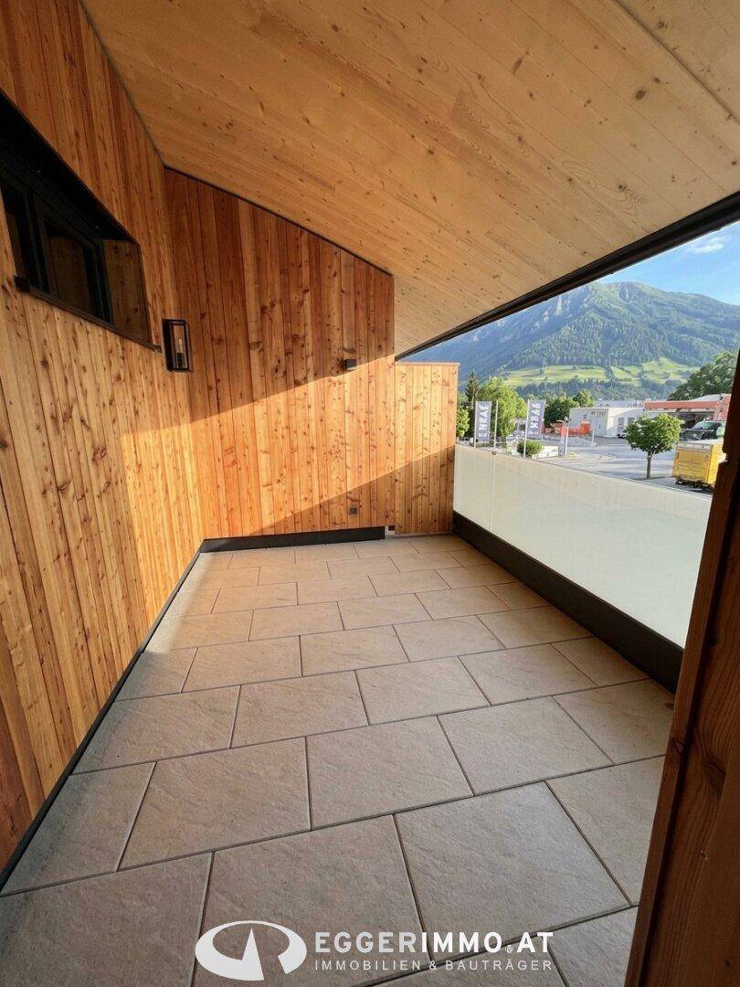 Geräumiger Balkon mit Fliesenboden, Holzverkleidung und Bergblick.