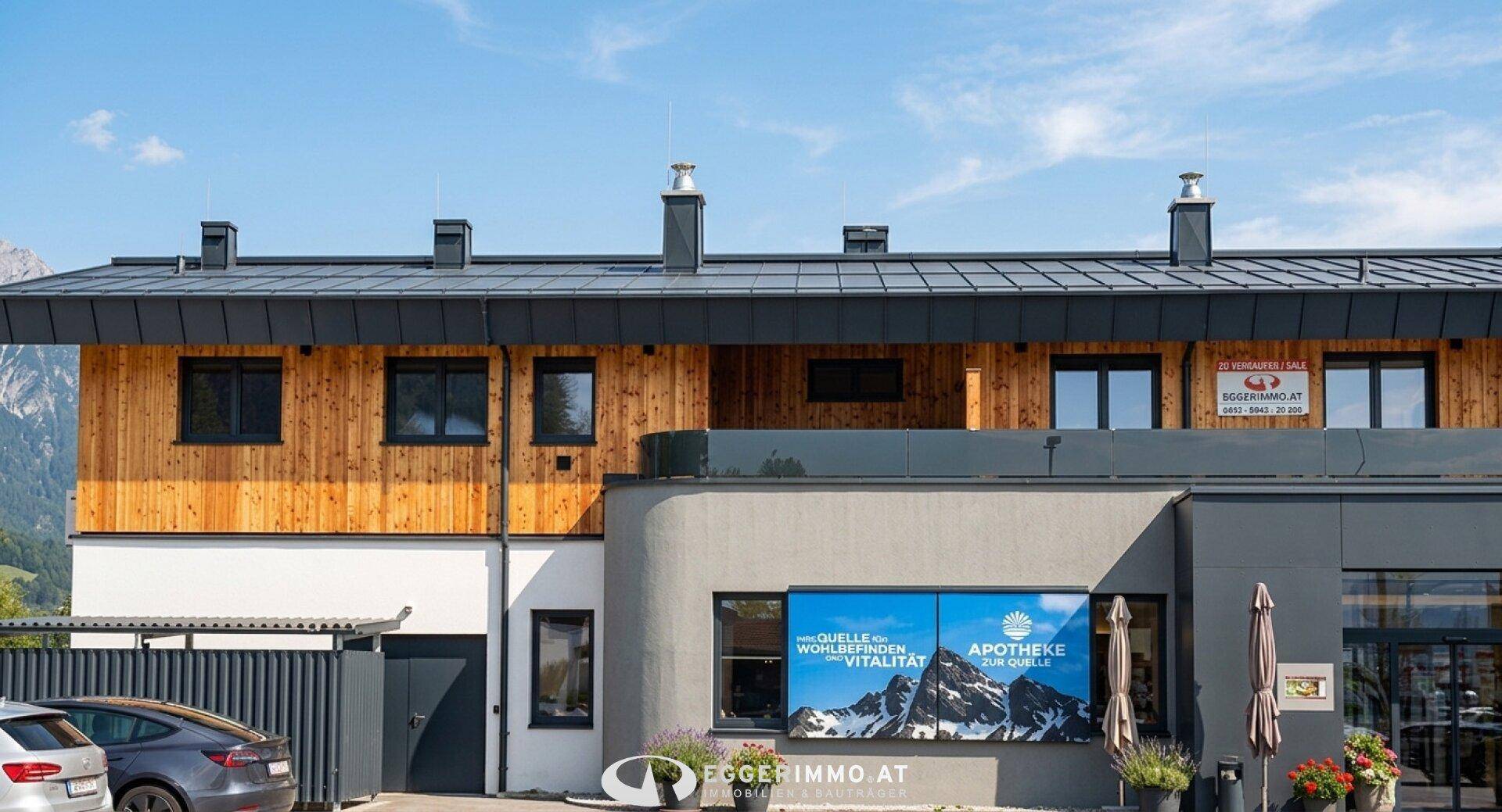 Moderne Gebäudefassade mit Holzverkleidung, Flachdach und großen Fenstern.