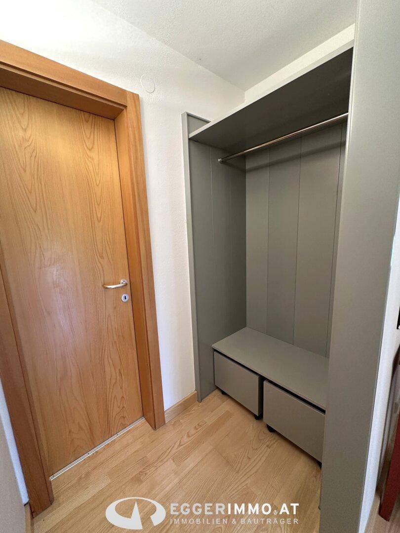 Eingangsbereich mit Holzboden und integrierter Garderobe für Jacken und Schuhe.