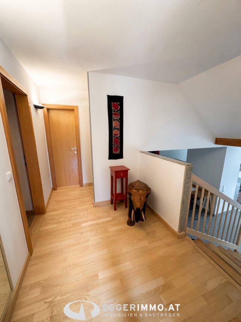 Geräumiger Flur mit Holztreppe, Parkettboden und Zugang zu weiteren Räumen.