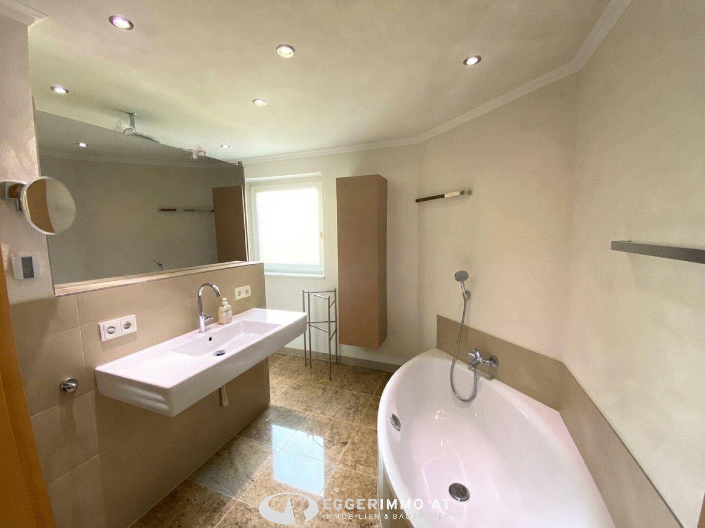 Modernes Badezimmer mit großem Waschbecken, Badewanne und Fliesenboden.