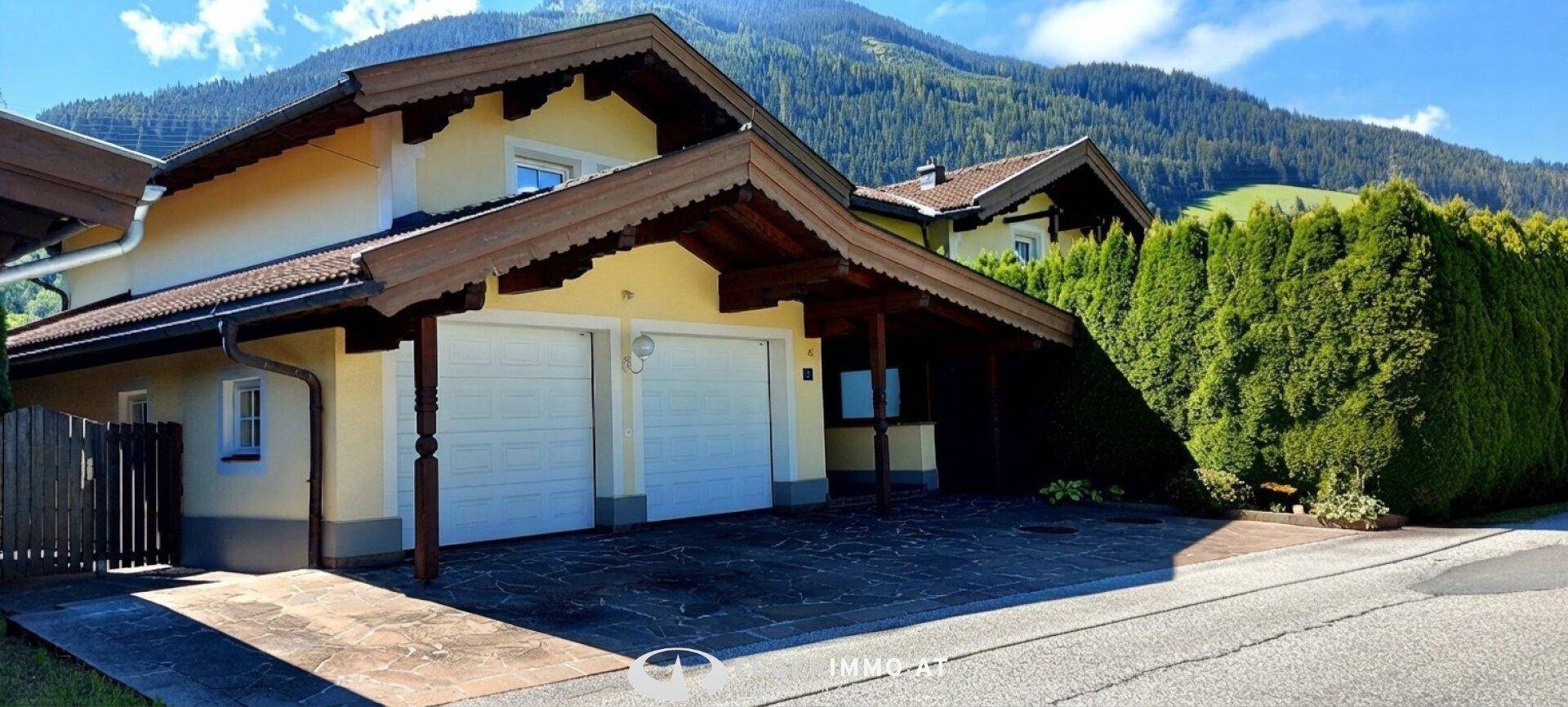 Vorderansicht des Hauses mit Doppelgarage, Carport und gepflasterter Auffahrt.