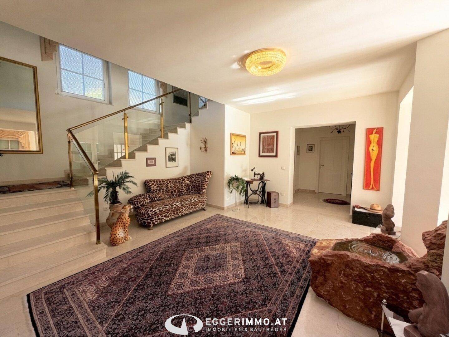 Geräumiger Eingangsbereich mit Marmorboden, eleganter Treppe und dekorativen Elementen.