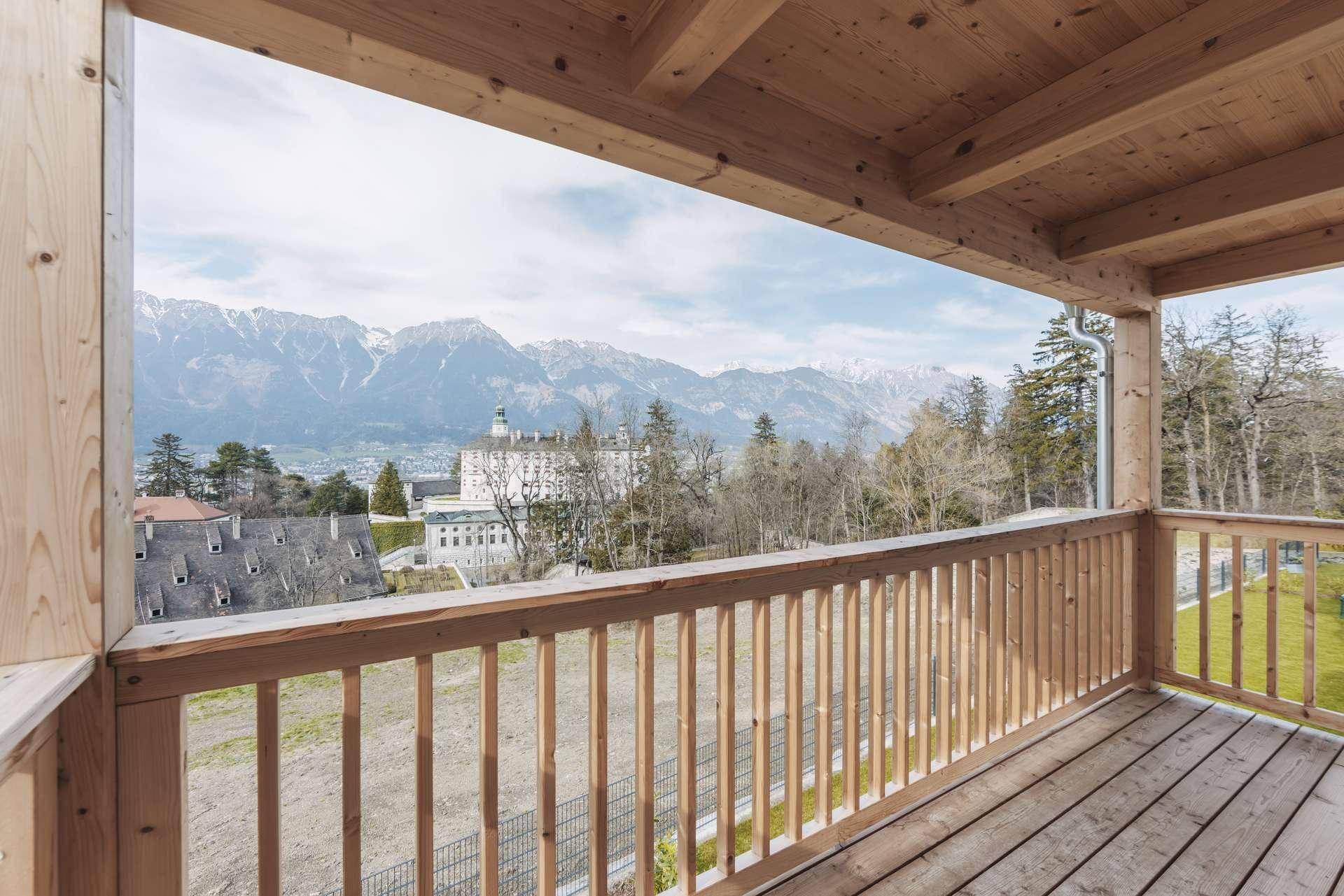 Geräumiger Holzbalkon mit weitem Blick über die Landschaft und die Berge.
