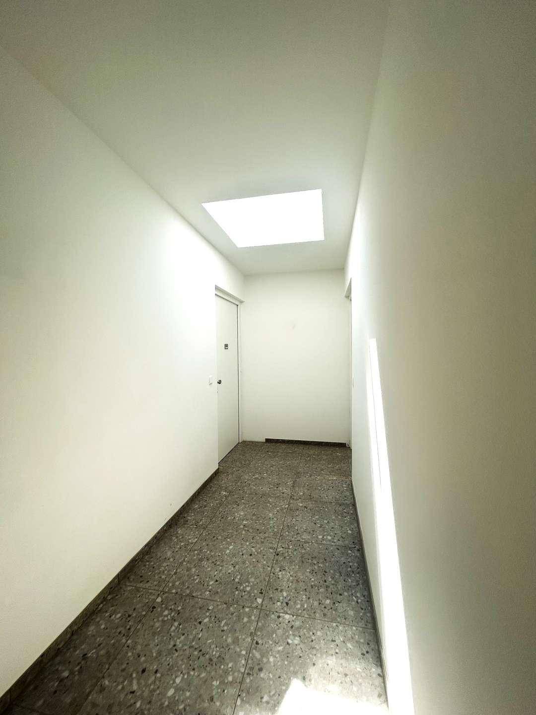 Heller Flur mit Terrazzoboden und natürlichem Licht durch ein Oberlicht.