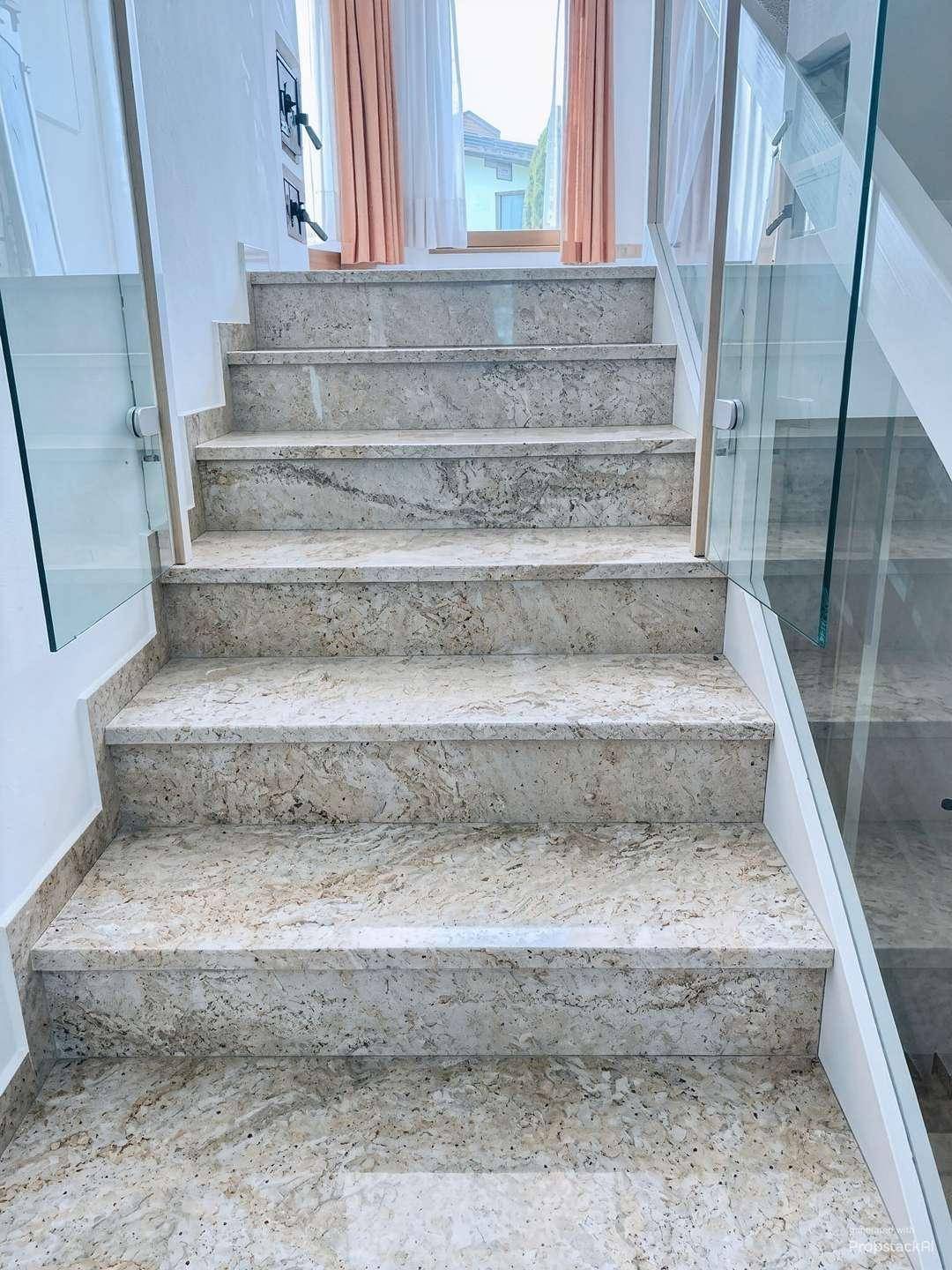 Stilvolle Treppe mit Granitstufen und transparenter Glasbrüstung, die Eleganz verleiht.