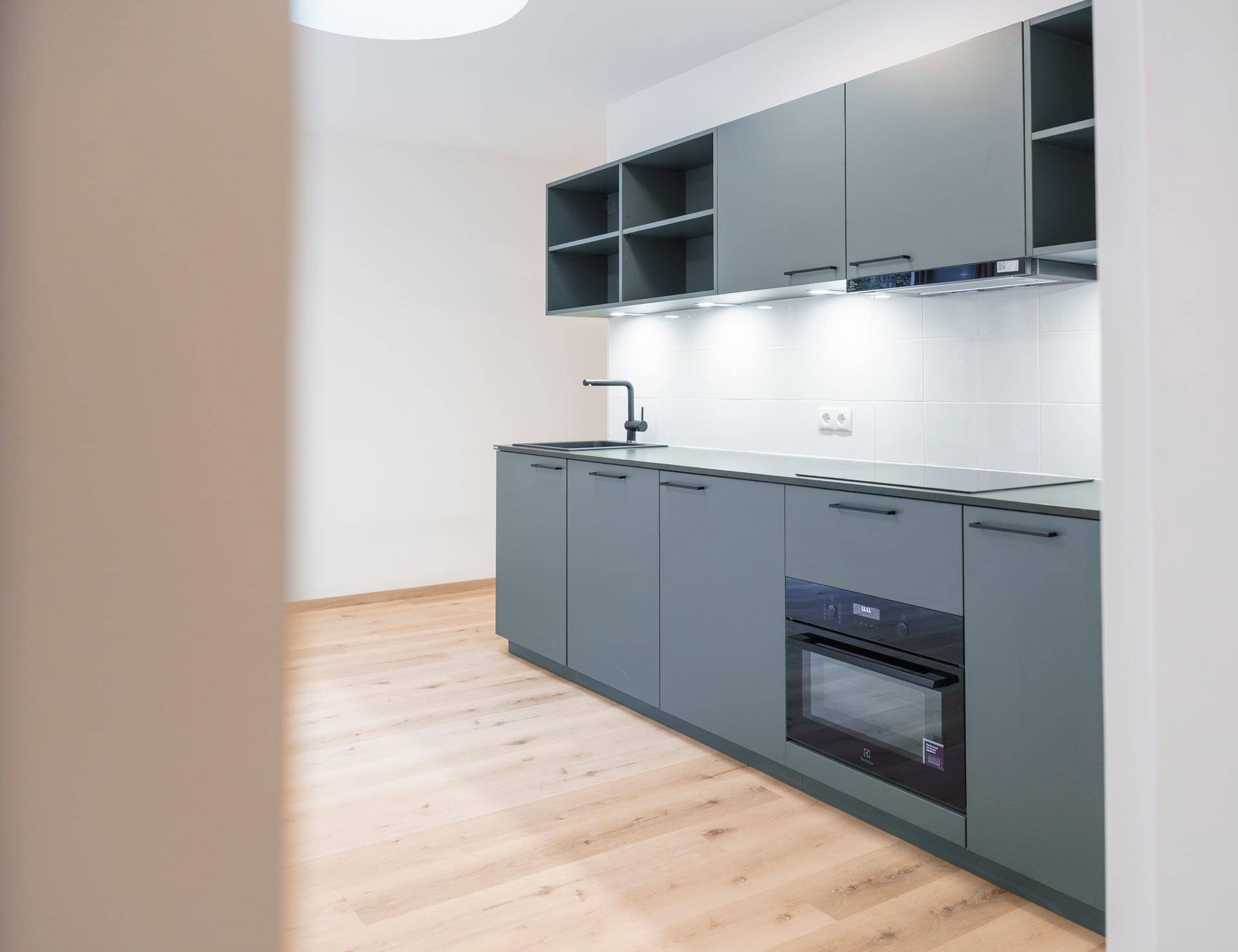 Detailansicht der modernen Küchenzeile mit grauen Schränken, integriertem Backofen und Induktionskochfeld.