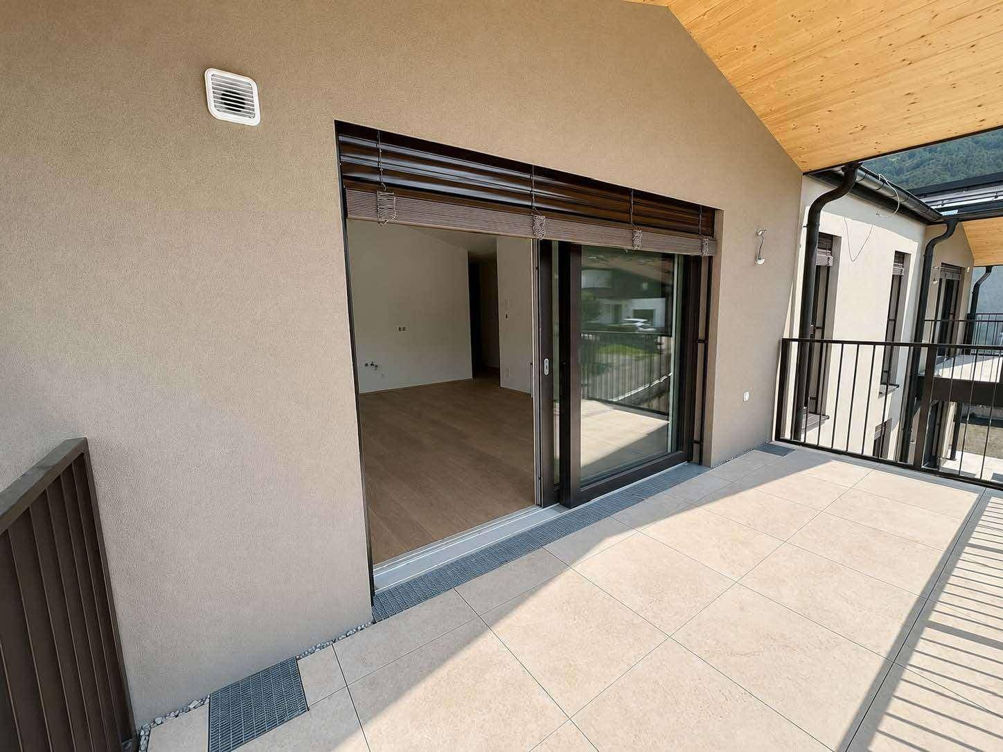 Geräumiger Balkon mit Fliesenboden und Zugang zu einem hellen Innenraum.
