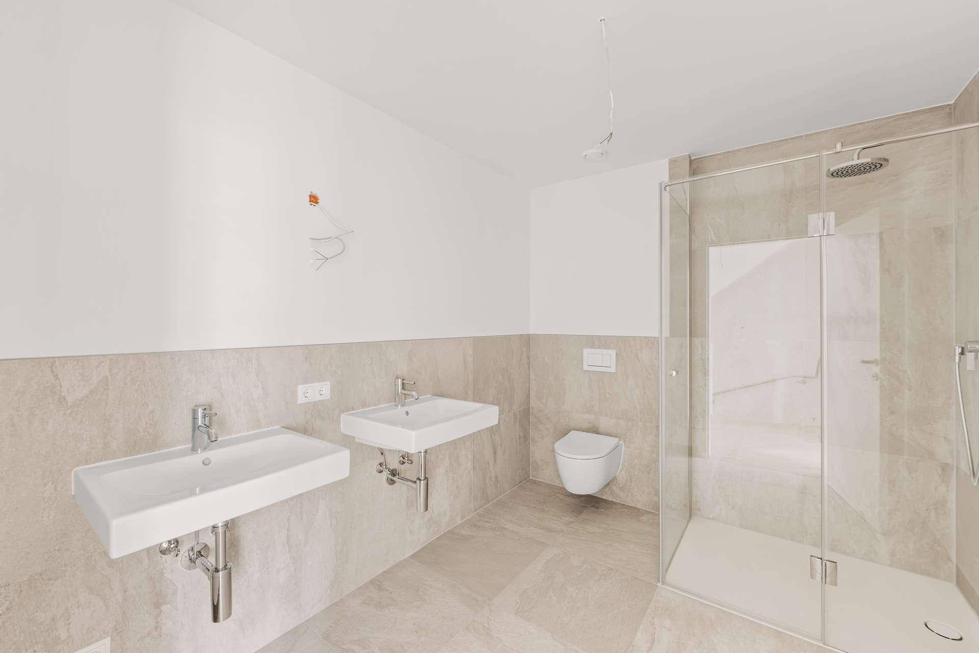 Geräumiges Badezimmer mit Doppelwaschbecken, Duschkabine und modernen Fliesen.