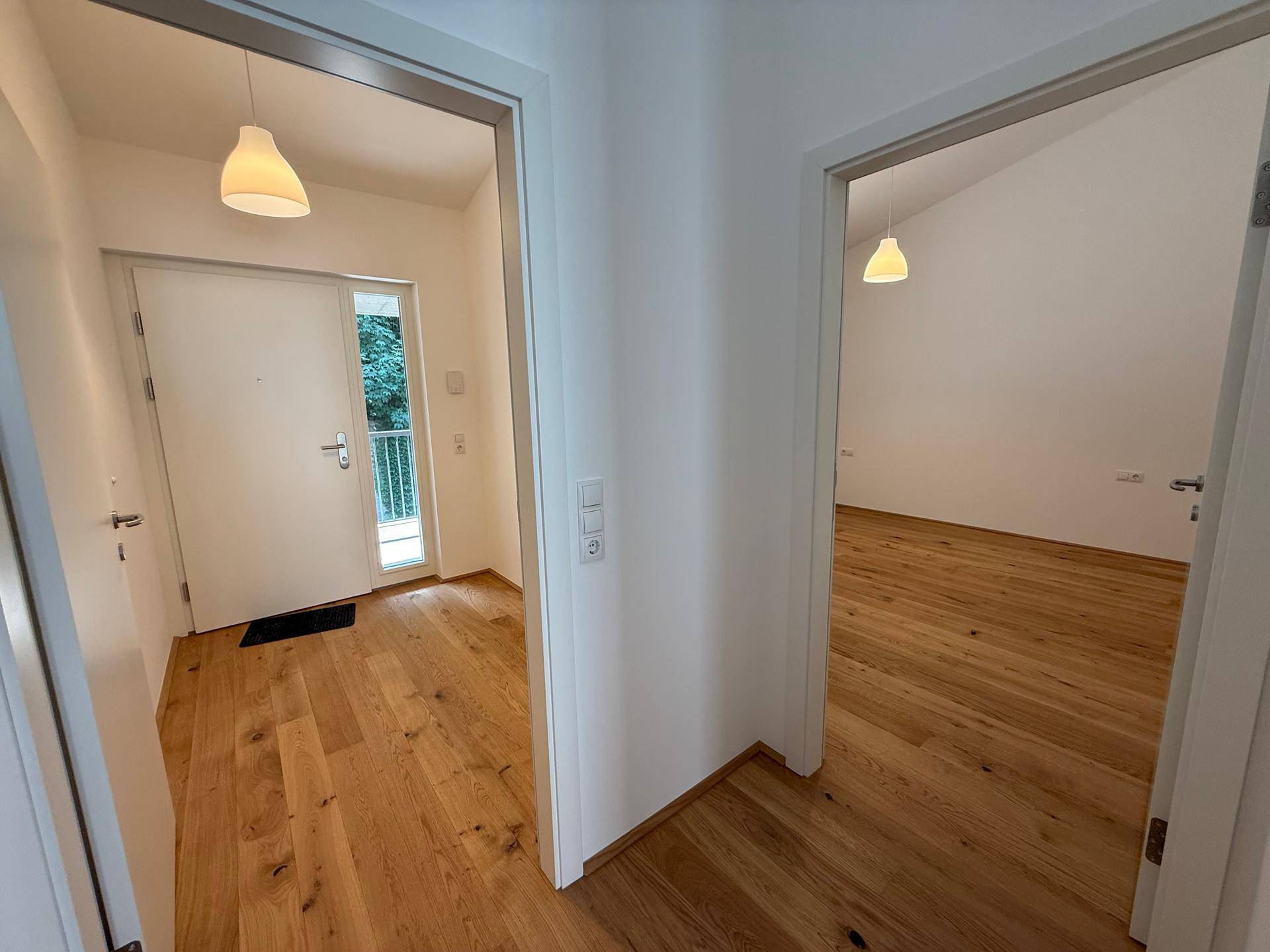 Heller Eingangsbereich mit Holzboden und Zugang zu verschiedenen Zimmern der Wohnung.