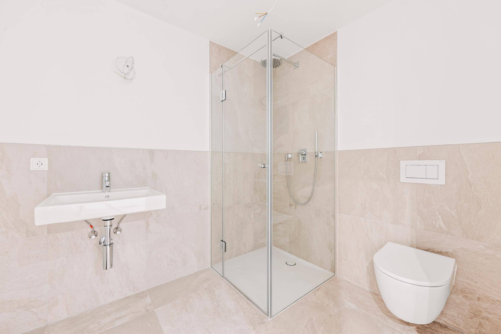 Modernes Badezimmer mit Duschkabine, wandhängendem WC und hellem Fliesenboden.