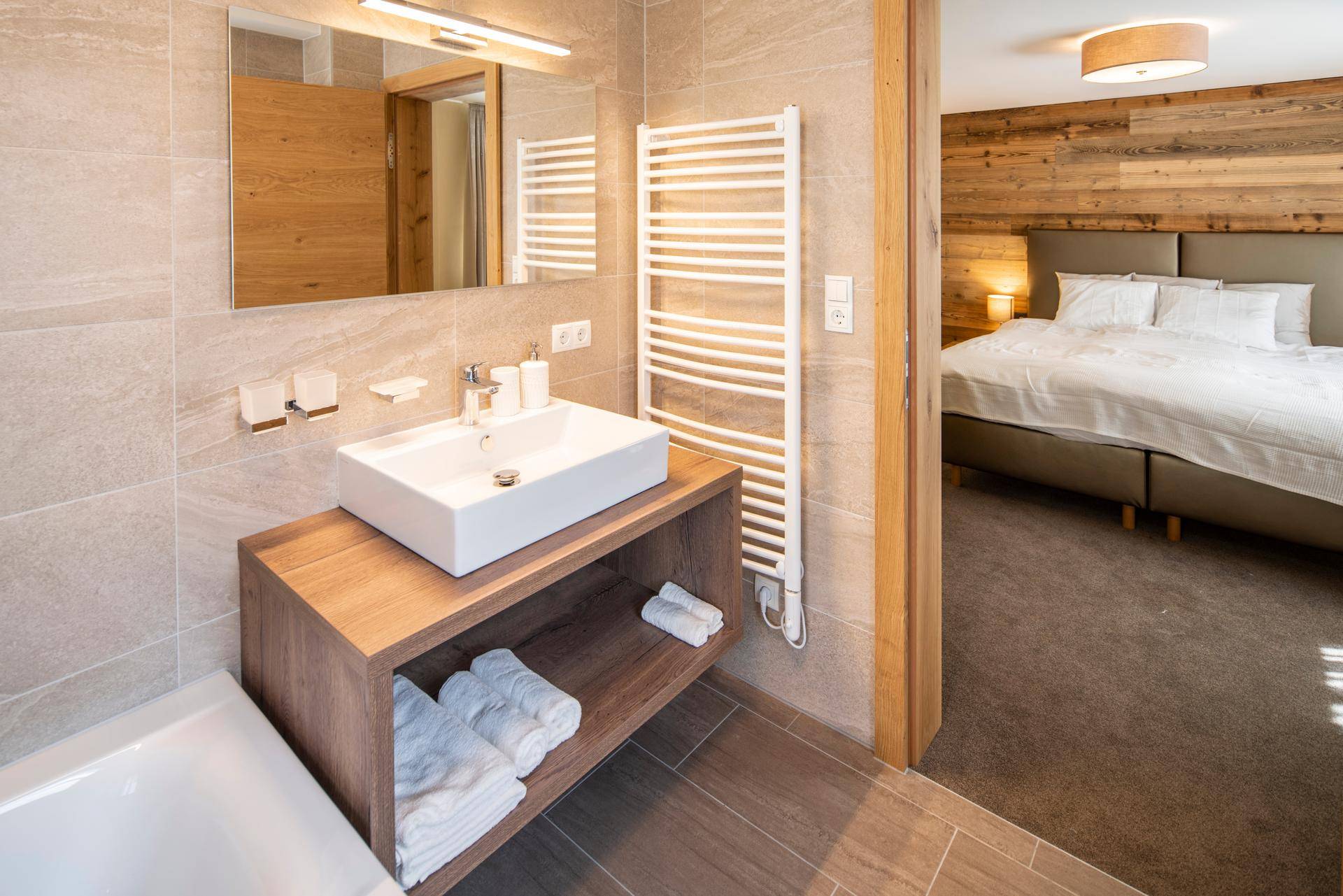 Modernes Badezimmer mit Waschtisch, beheiztem Handtuchhalter und Zugang zum Schlafzimmer.