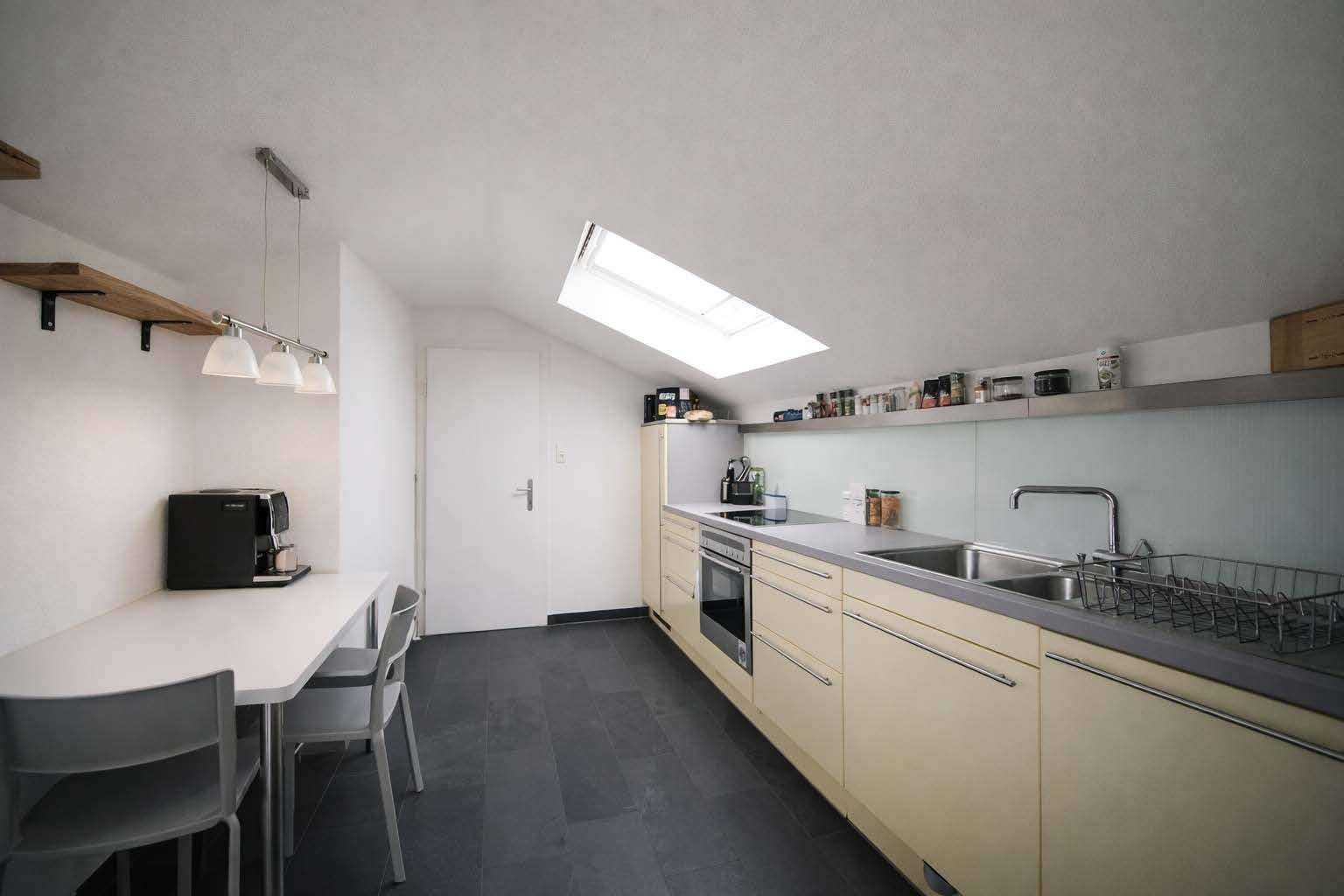 Funktionale Küche mit Dachschräge, Einbauküche und kleinem Essbereich für den Alltag.