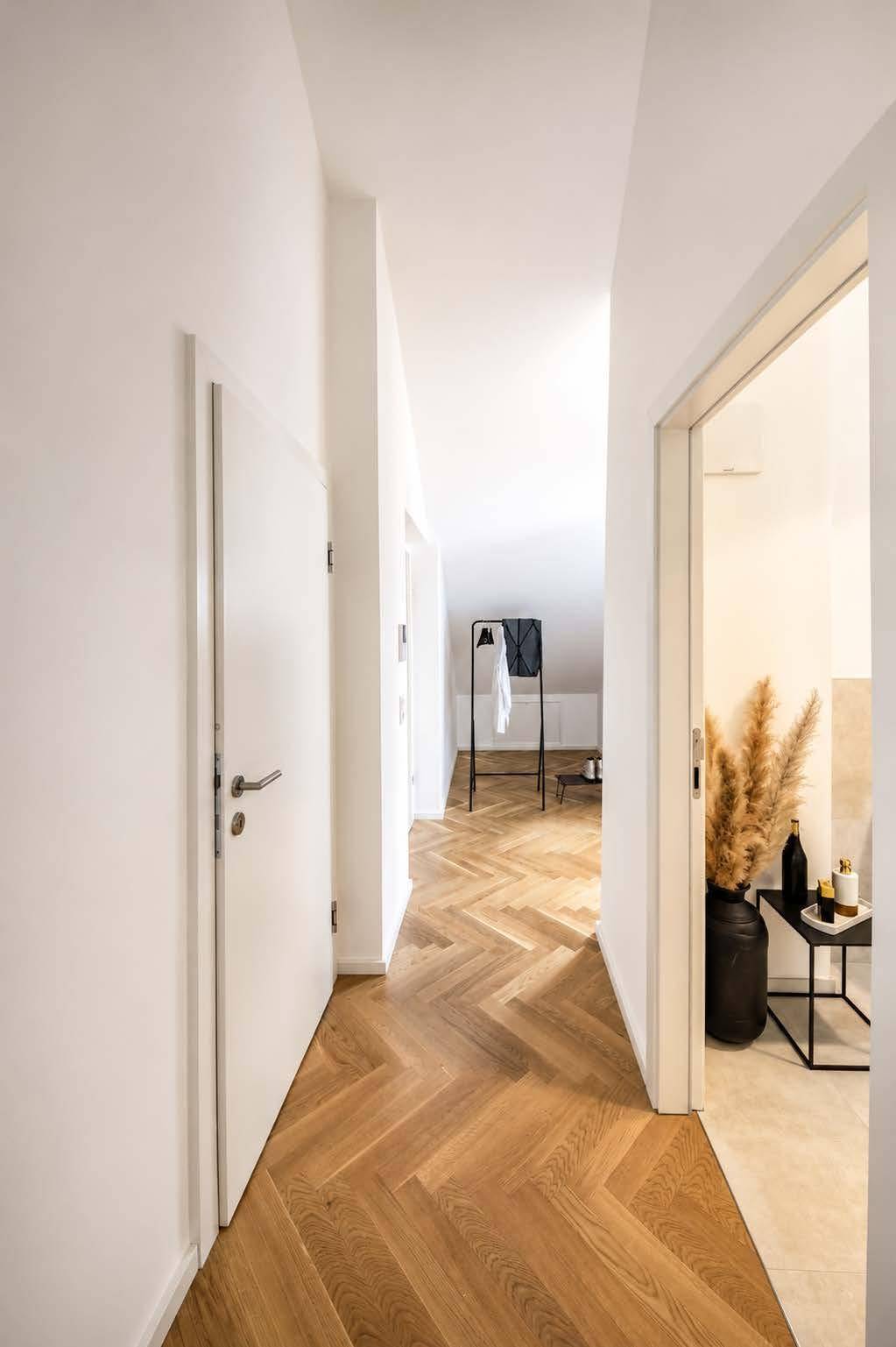 Heller Flur mit Fischgrätparkett und Zugang zu verschiedenen Zimmern in der Wohnung.