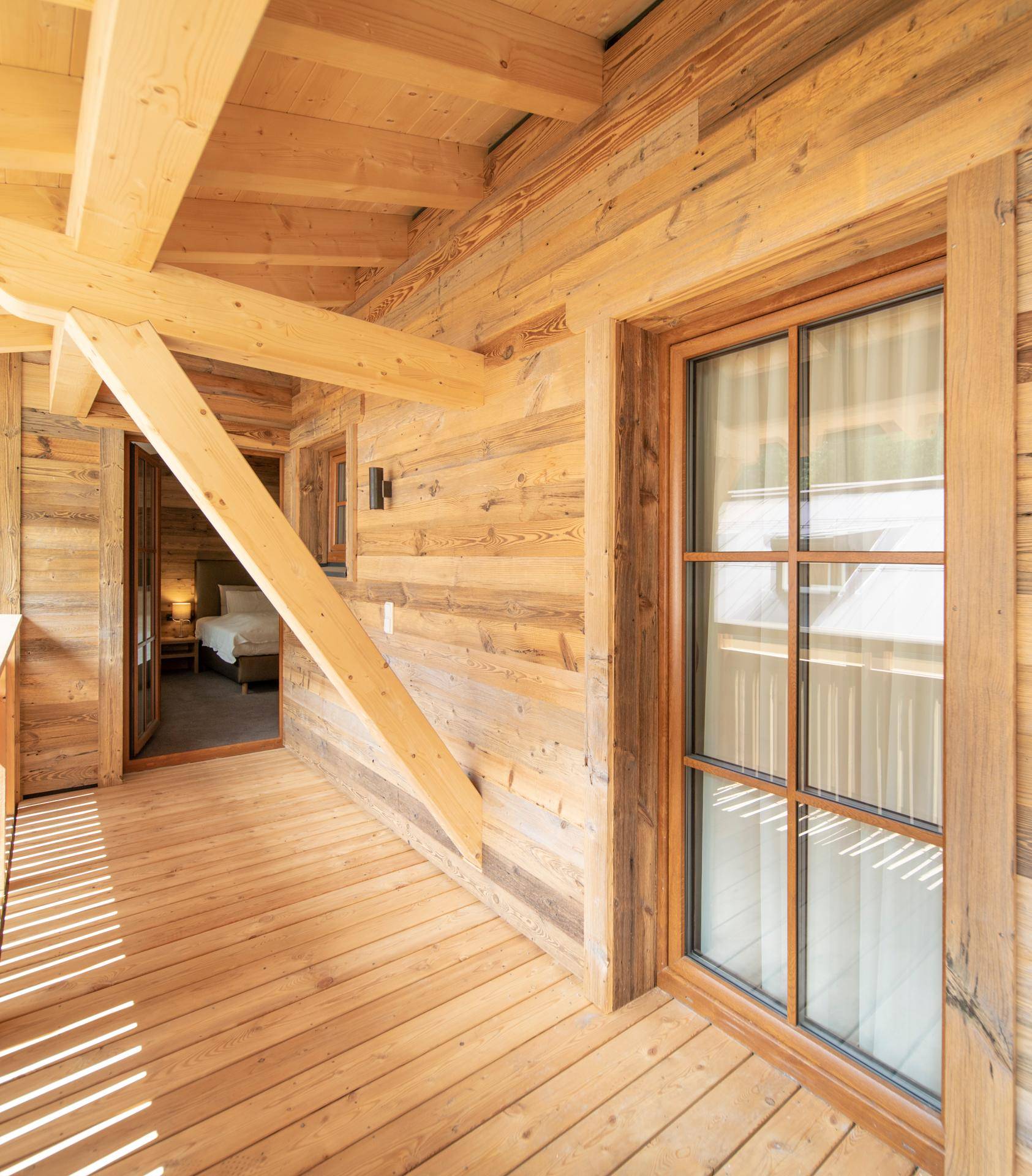 Geräumiger Holzbalkon mit Blick auf die Umgebung und Zugang zum Schlafzimmer.