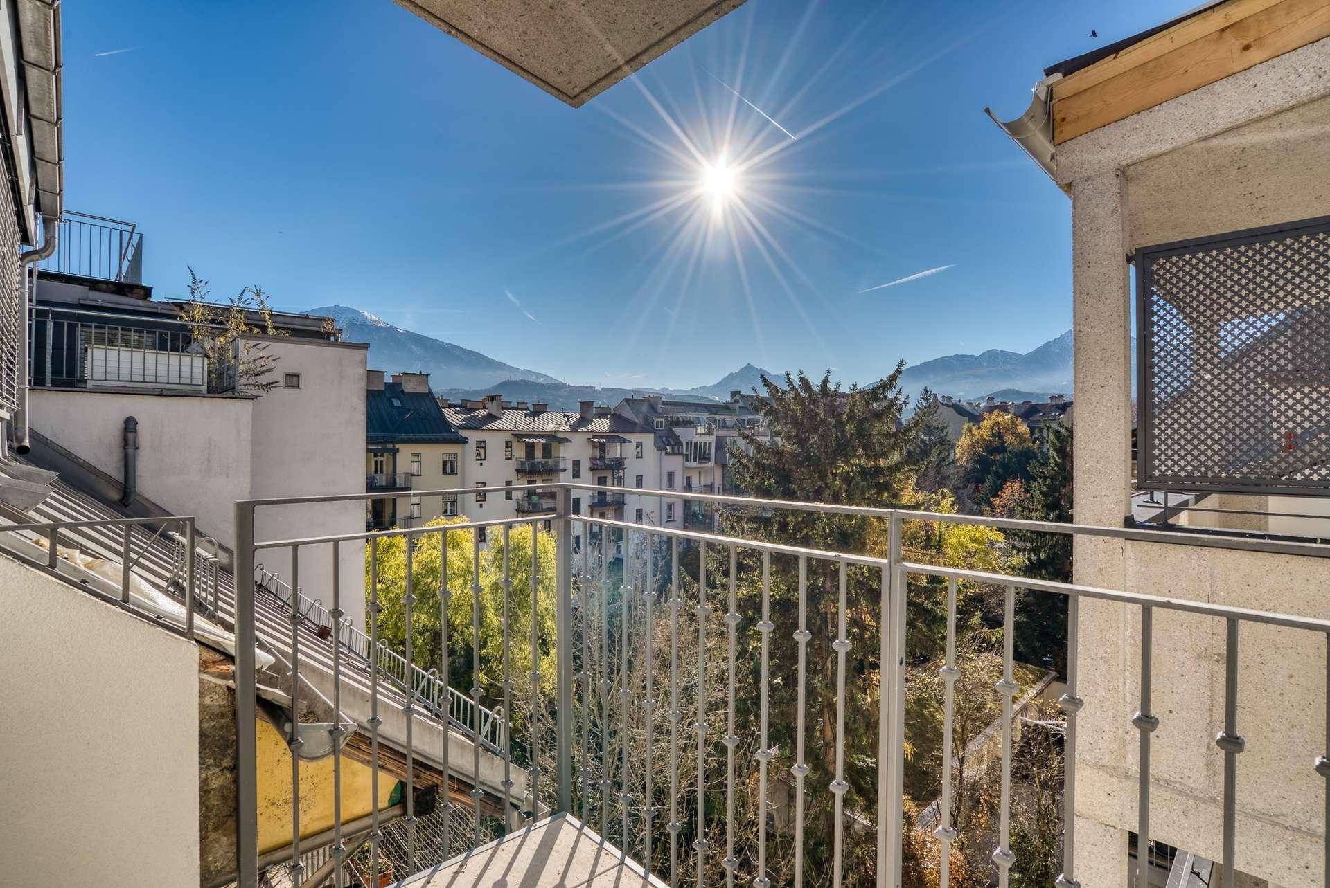 Sonniger Balkon mit Bergblick und Blick über die Stadt an einem klaren Tag.