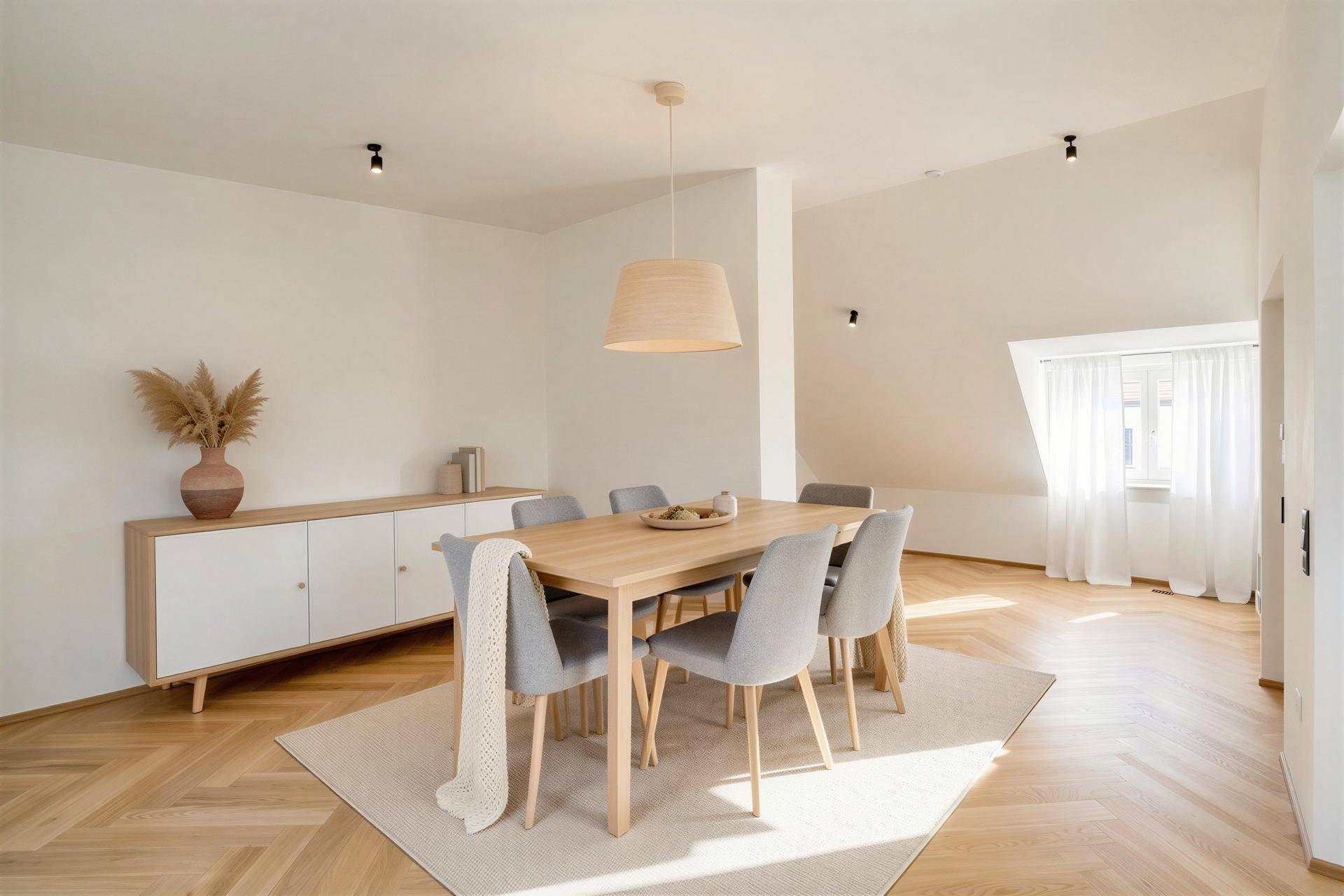 Geräumiger Essbereich mit Holztisch, Sideboard und Parkettboden in Fischgrätmuster.