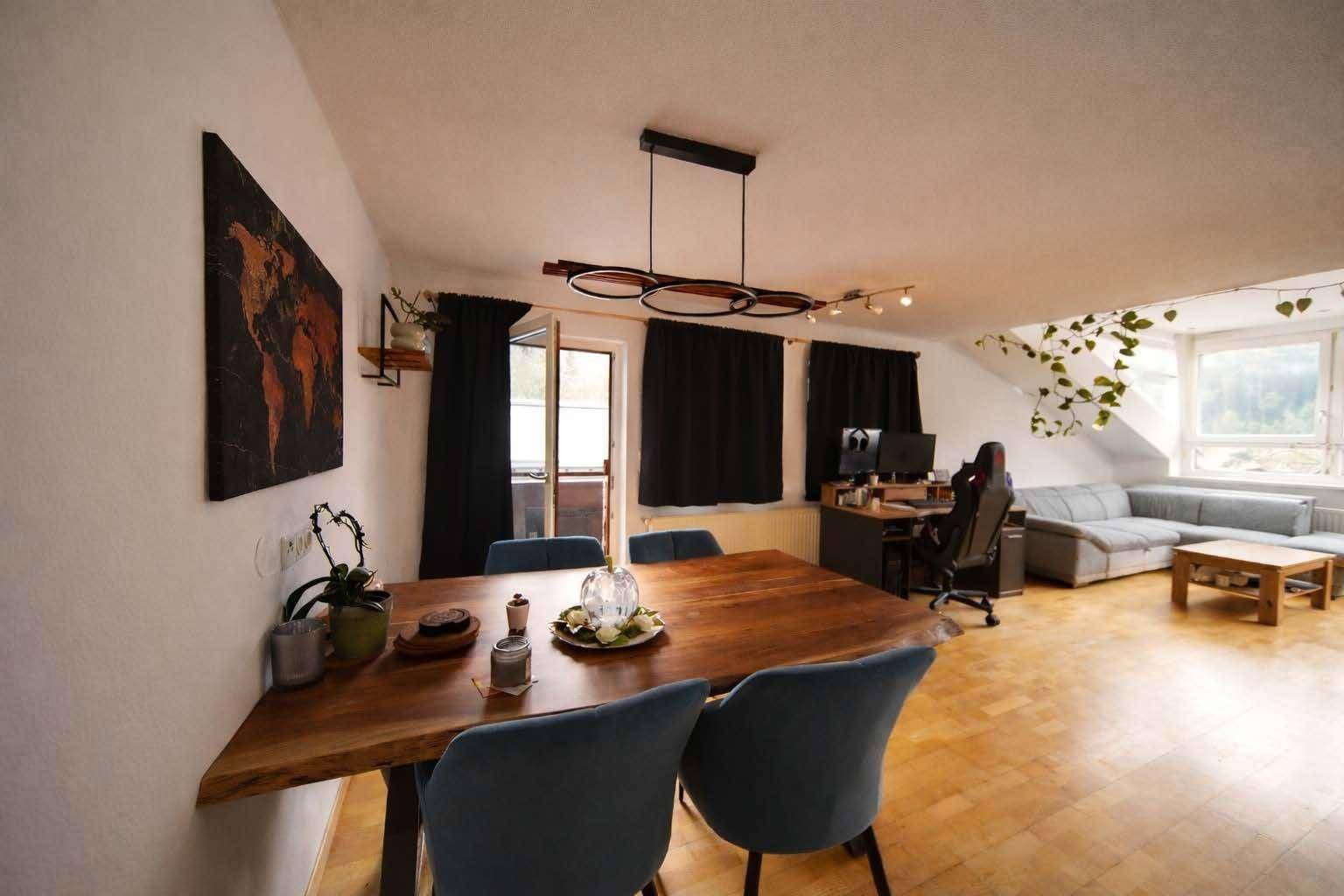 Offener Wohn- und Essbereich mit Holztisch, Stühlen und Zugang zum Balkon.