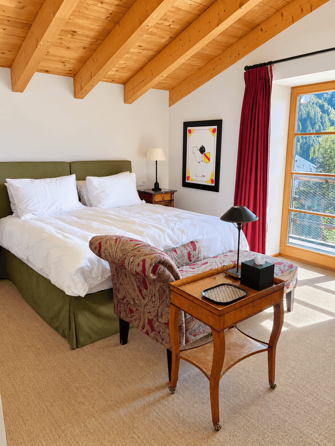 Gemütliches Schlafzimmer mit Holzbalkendecke, Bergblick und rotem Vorhang.
