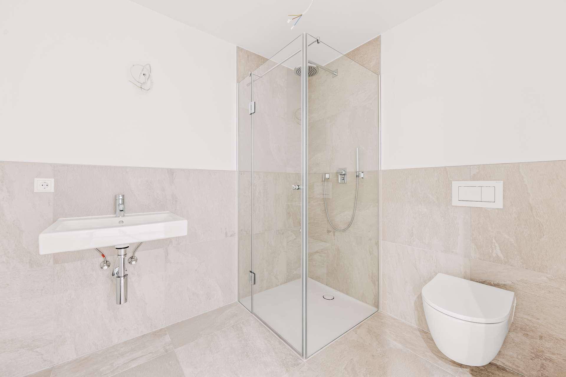 Modernes Badezimmer mit Duschkabine, Wand-WC und hellen Fliesen.