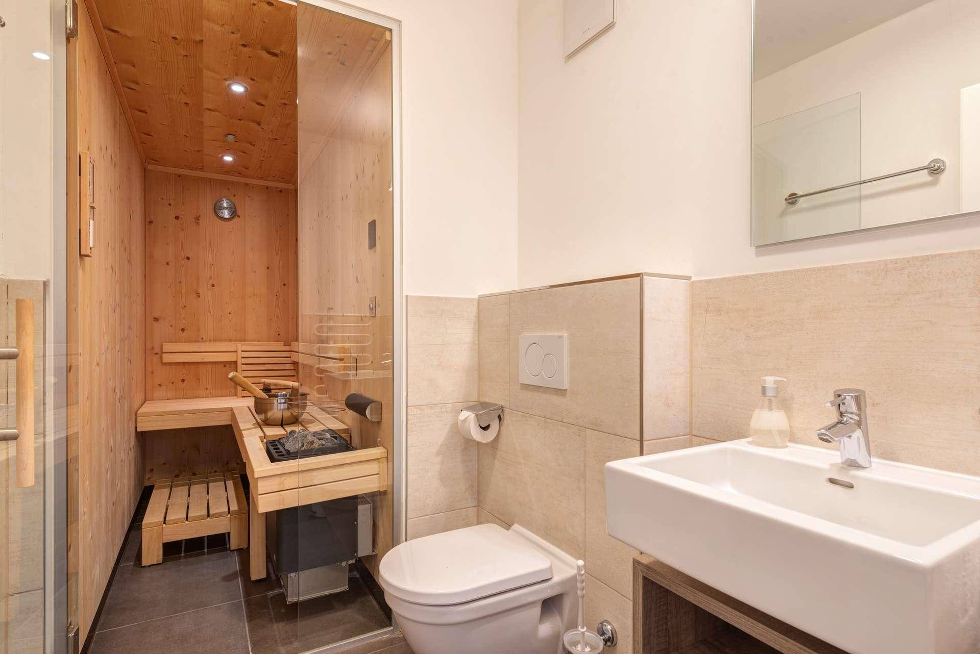 Modernes Badezimmer mit integrierter Sauna, Dusche und Wand-WC.