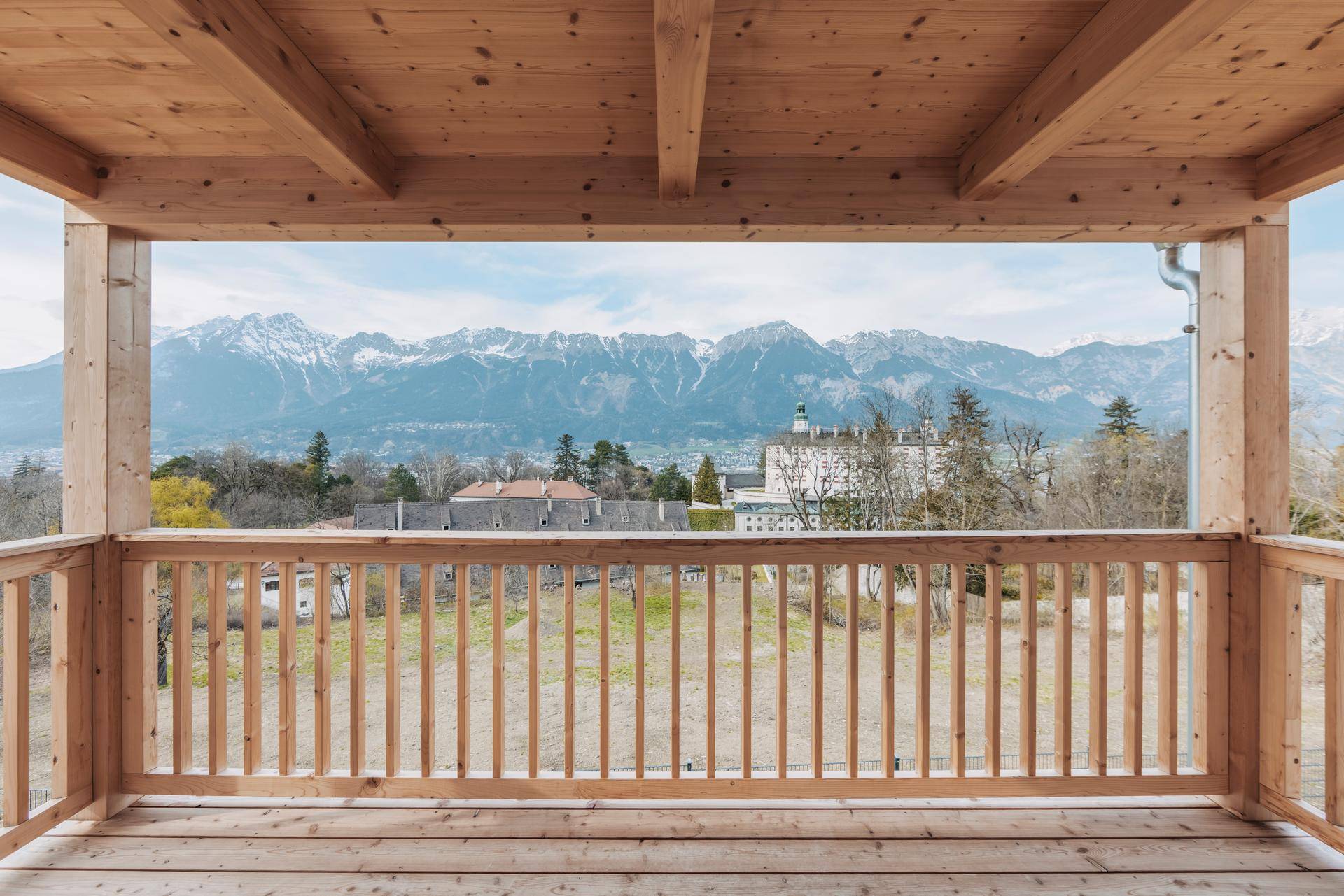 Überdachter Holzbalkon mit atemberaubendem Panoramablick auf die Berge und das Schloss.
