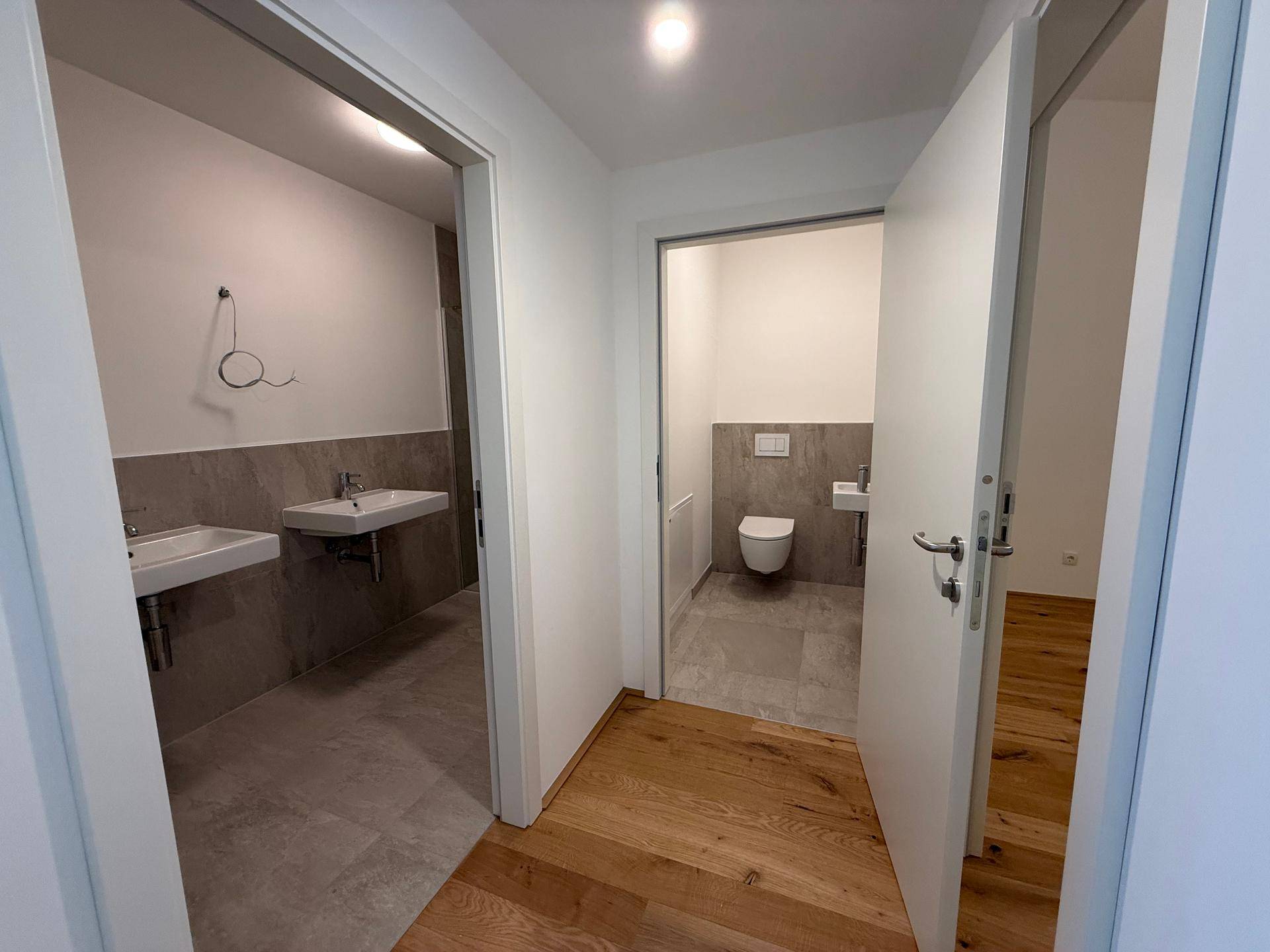 Flur mit Zugang zu einem modernen Badezimmer und einer separaten Gästetoilette.
