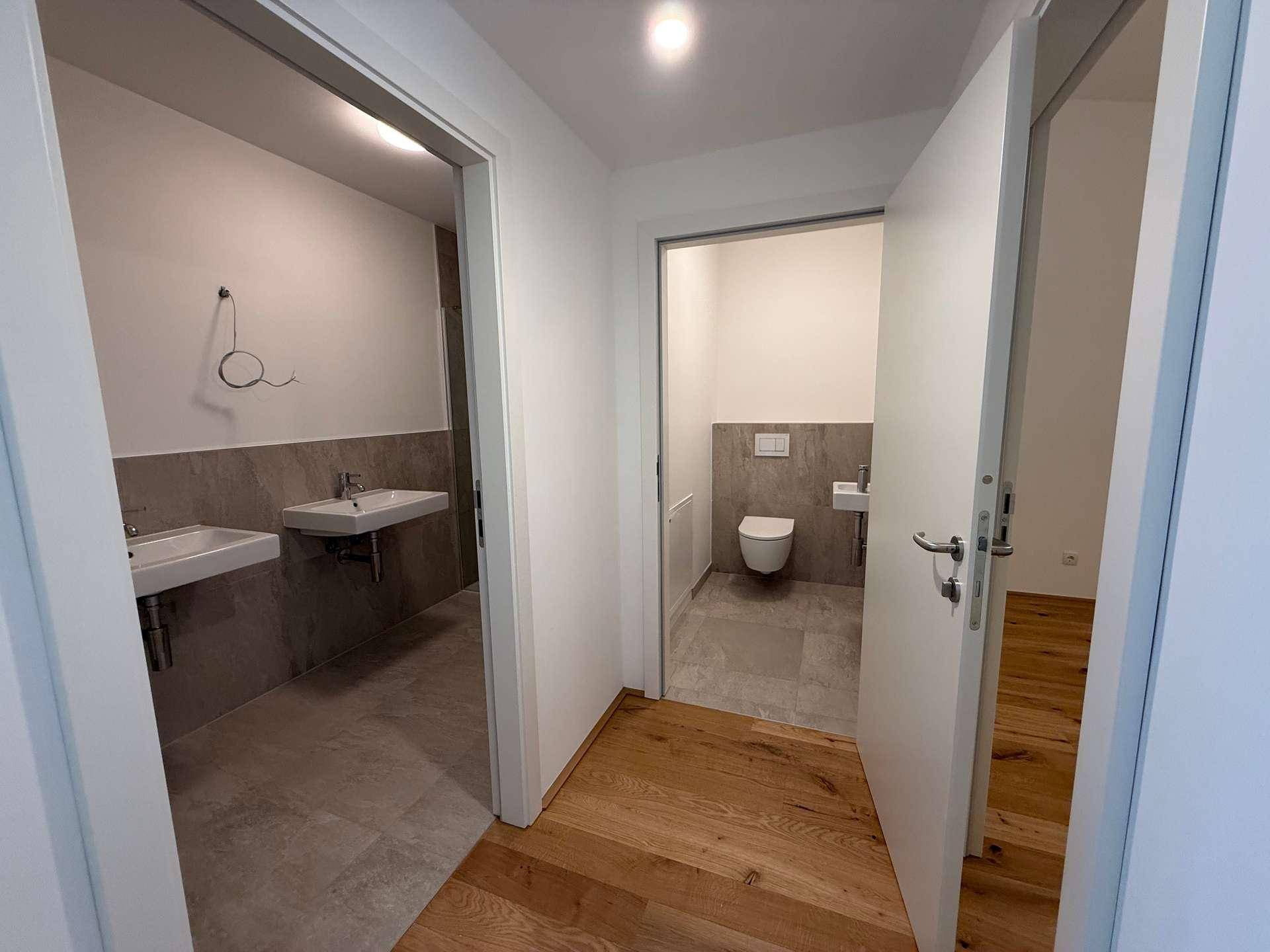 Flur mit Zugang zu einem modernen Badezimmer und einer separaten Gästetoilette.