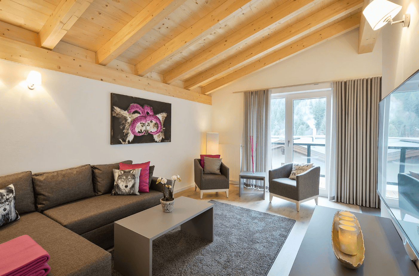Helles Wohnzimmer mit Holzbalkendecke, gemütlichem Sofa und Zugang zum Balkon.